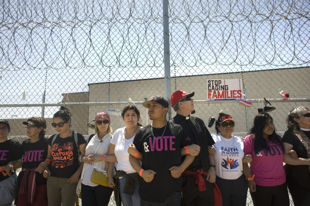 Group of people holding arms in protest of immigrants families separation