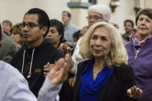 Young latino man and older latino woman holding hands during mass